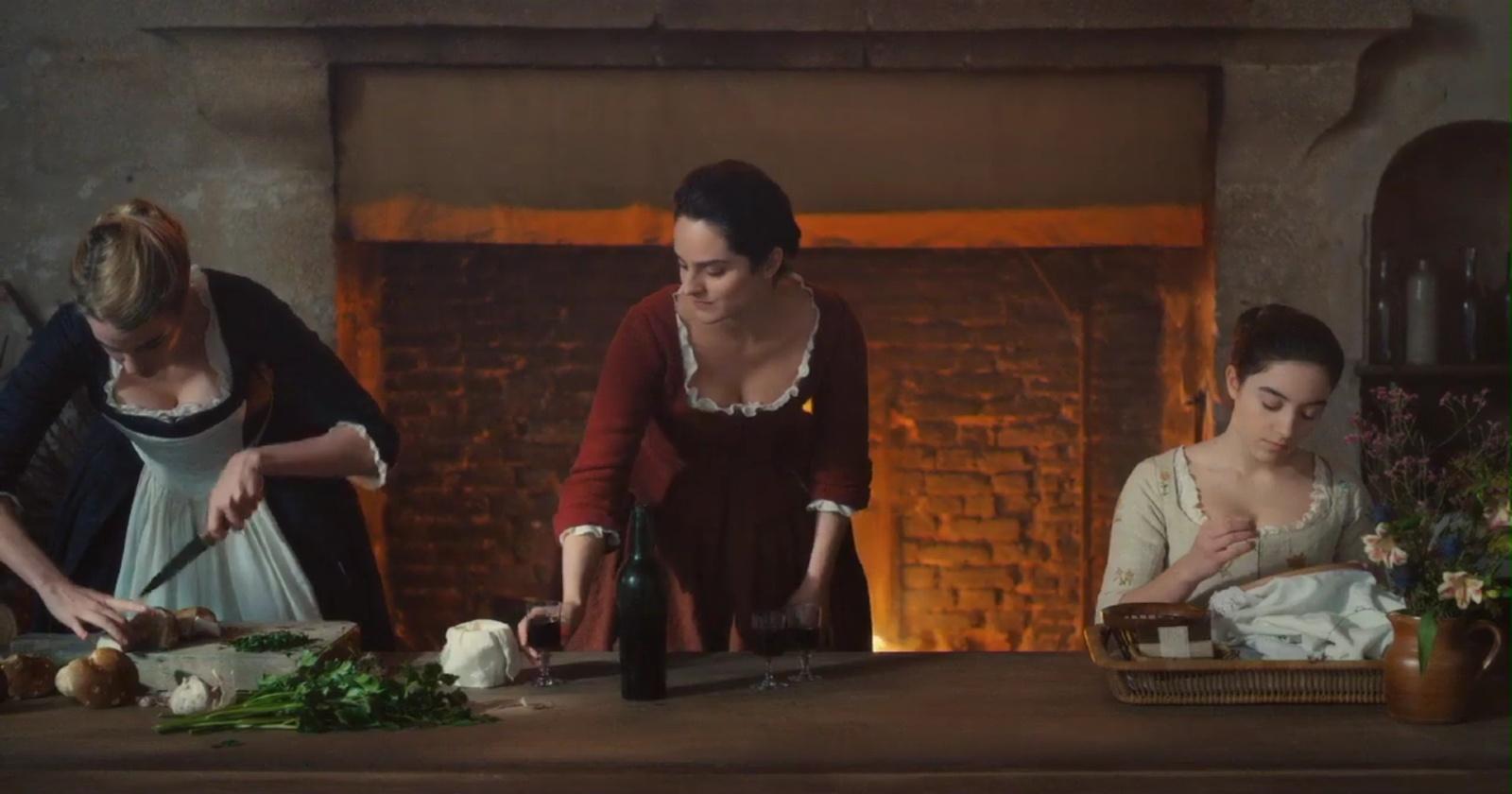 Adèle Haenel como Héloïse, Noémie Merlant como Marianne y Luàna Bajrami como Sophie en Portrait of a Lady on Fire sentadas en la mesa de la casa cocinando
