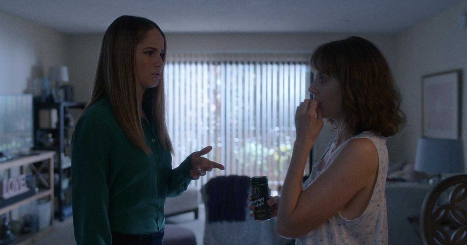 Alison Brie como Sarah y Debby Ryan como Nikki conversando en un departamento en La chica que amaba los caballos
