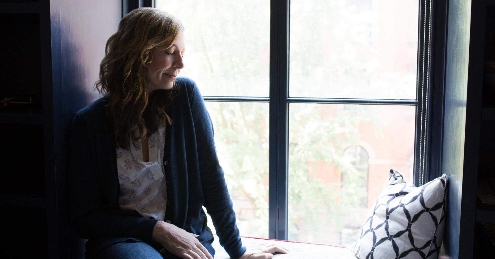 Allison Janney como Margo Mooney apoyada en una ventana sonriendo en la película Tallulah
