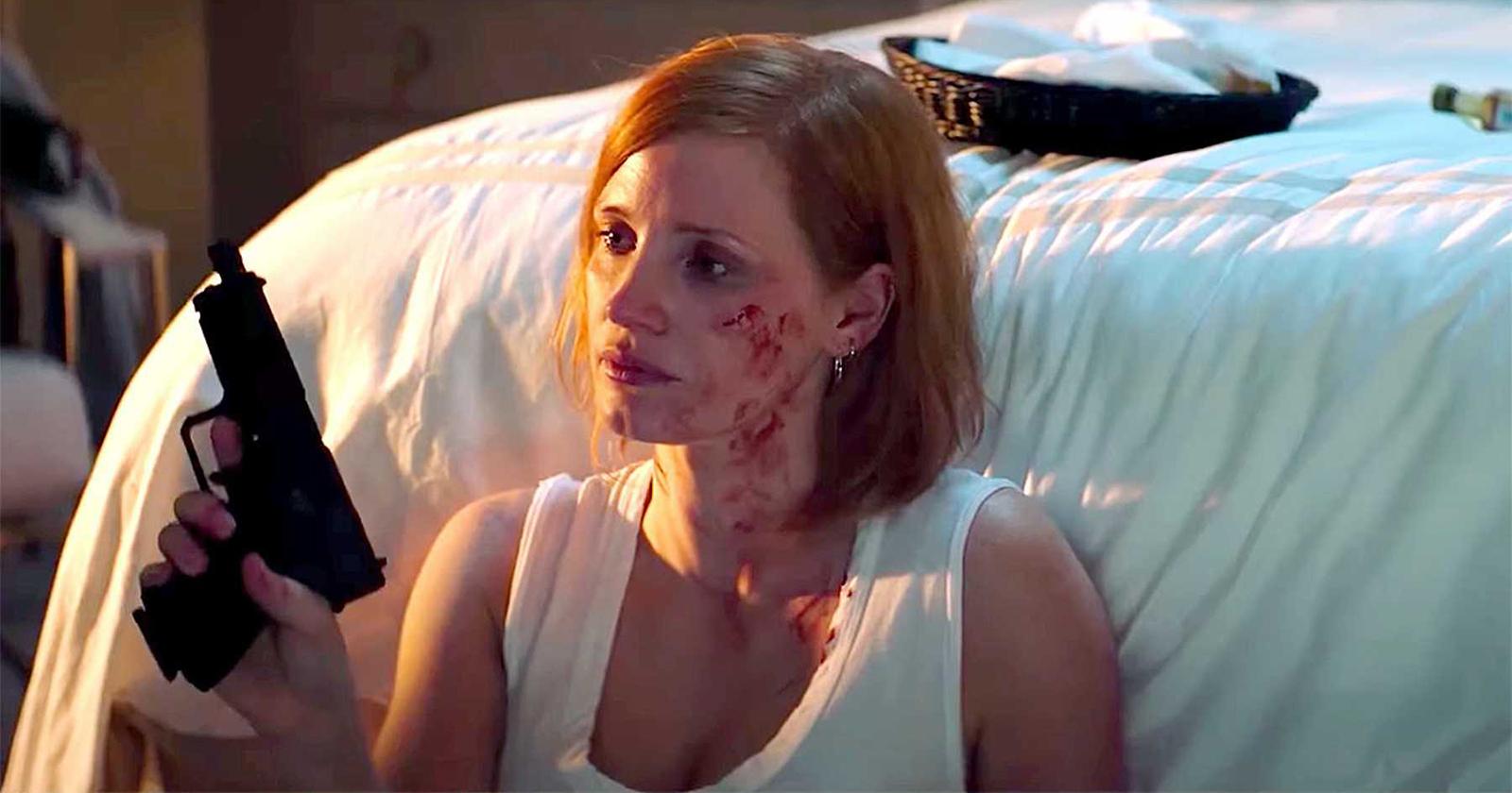 Jessica Chastain mirando fijamente un arma, con el rostro manchado de sangre. .