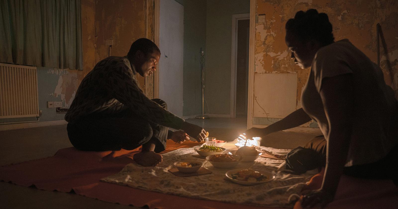 Personajes de Su casa, en una escena oscura, manipulando velas.