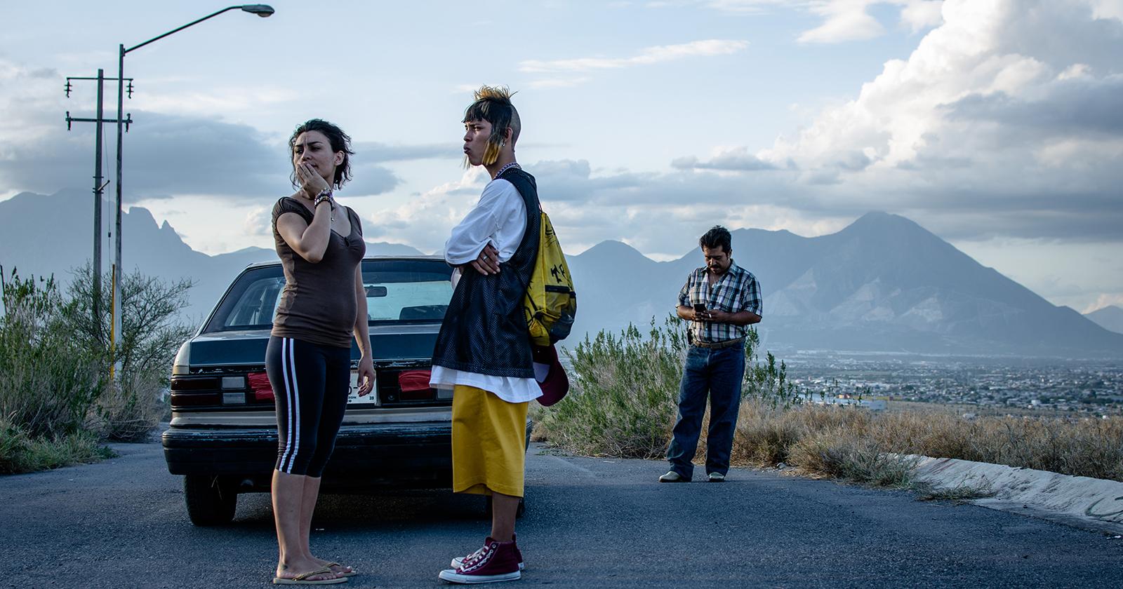 Escena de Ya no estoy aquí en que Ulises abandona Monterrey. Se le ve parado en una carretera, junto a un auto, despidiéndose de una mujer.